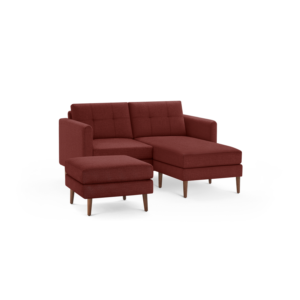 Modern sectional sofa with chaise lounge and matching ottoman, upholstered in textured dark red fabric with wooden legs.