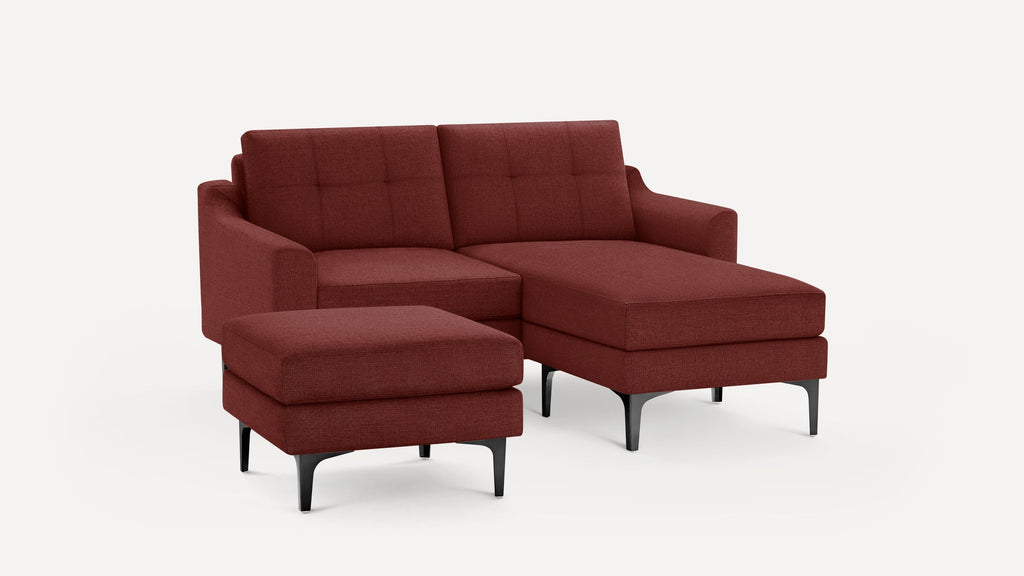 Modern deep red fabric sectional sofa with tufted cushions and black legs, accompanied by a matching ottoman.