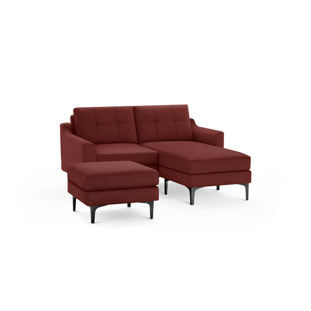 Modern sectional sofa with chaise lounge and matching ottoman in deep red fabric upholstery, featuring tufted back cushions and black tapered legs.