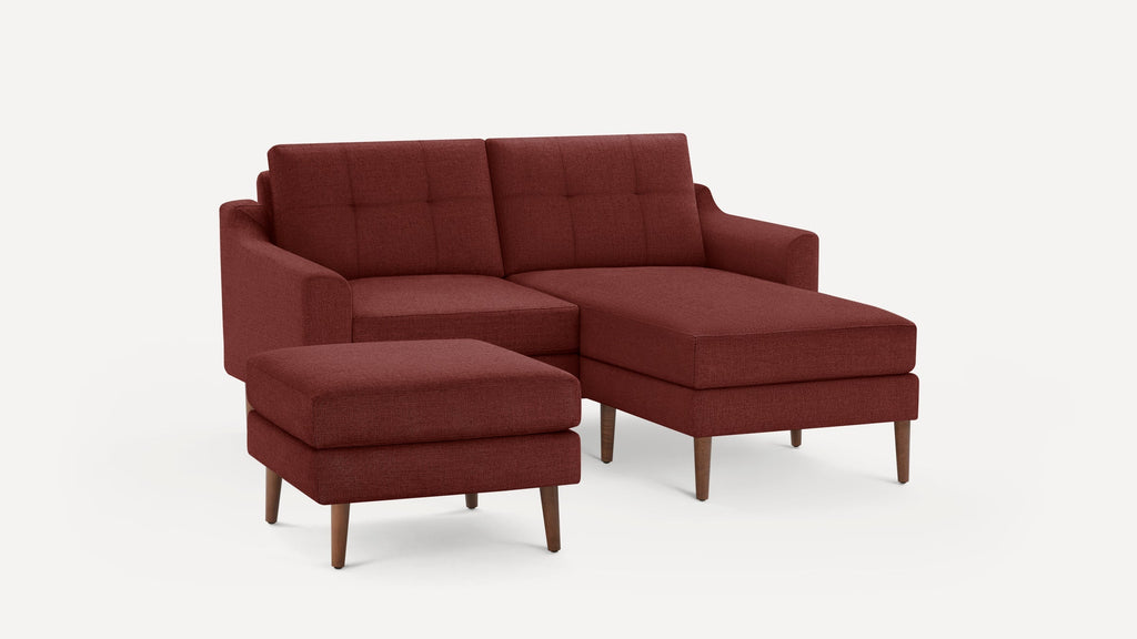 Modern L-shaped sectional sofa with matching ottoman, upholstered in deep red fabric and supported by wooden legs.