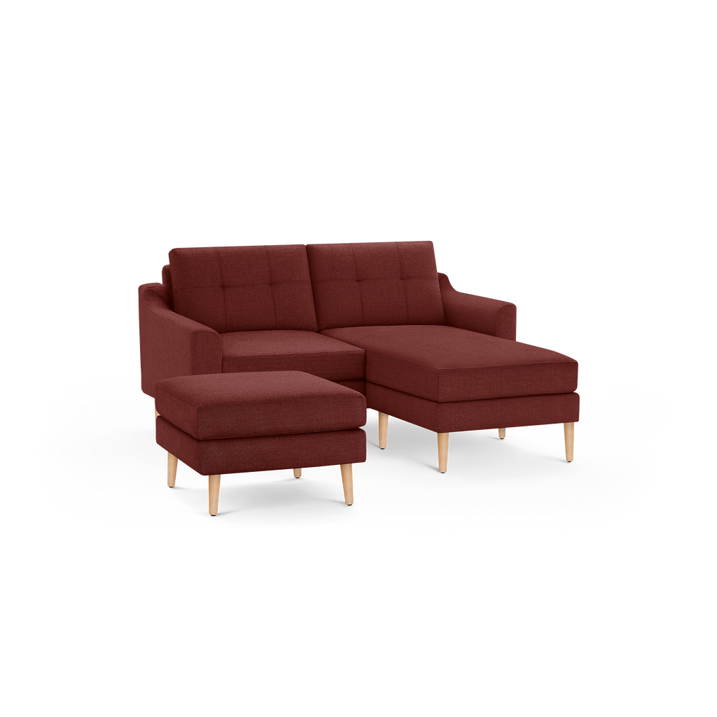 Modern rust-colored fabric sectional sofa with tufted back cushions and light wood tapered legs, including matching ottoman.