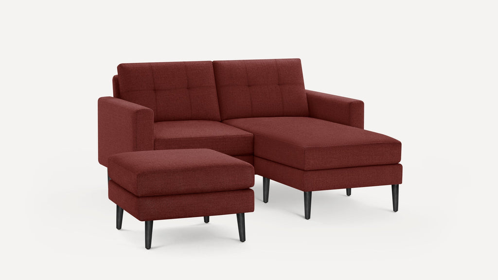 Modern sectional sofa with deep red fabric upholstery, tufted back cushions, and black tapered legs, featuring a matching ottoman.
