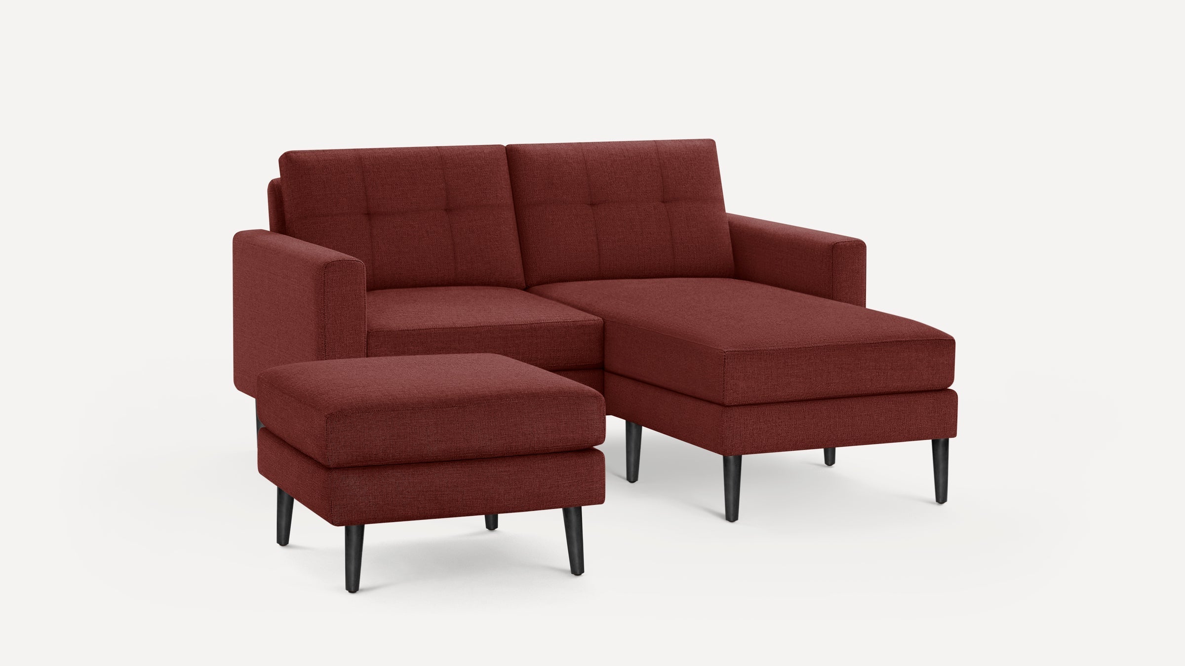 Modern sectional sofa with deep red fabric upholstery, tufted back cushions, and black tapered legs, featuring a matching ottoman.