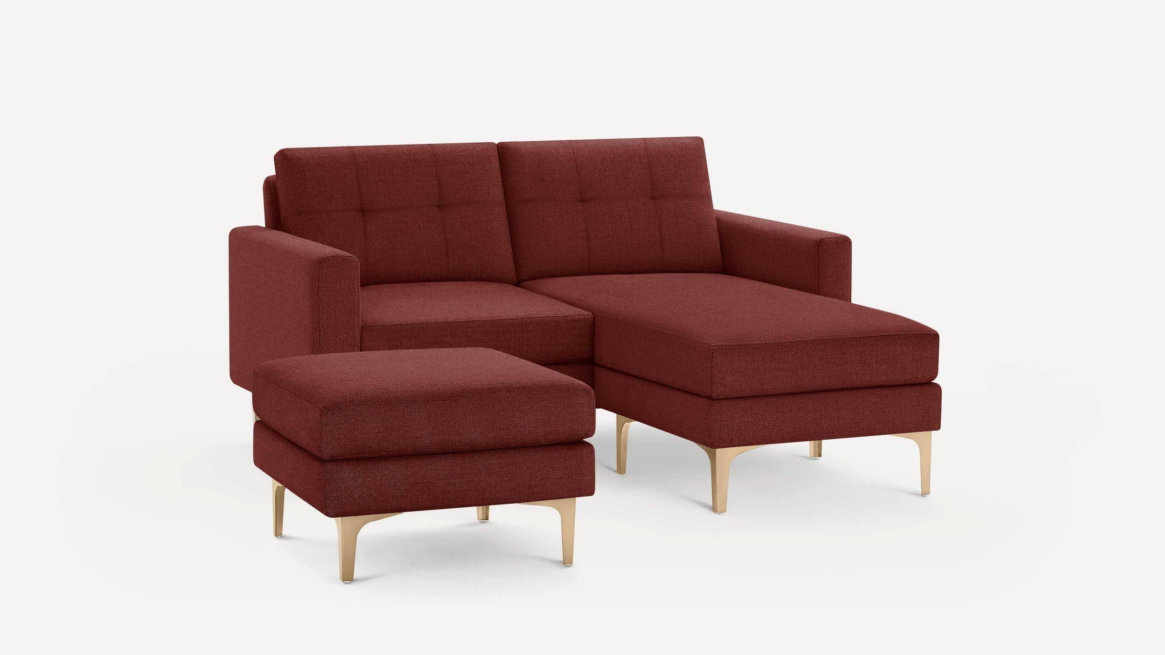 Modern sectional sofa in rich burgundy fabric with tufted cushions, gold metal legs, and a matching ottoman.