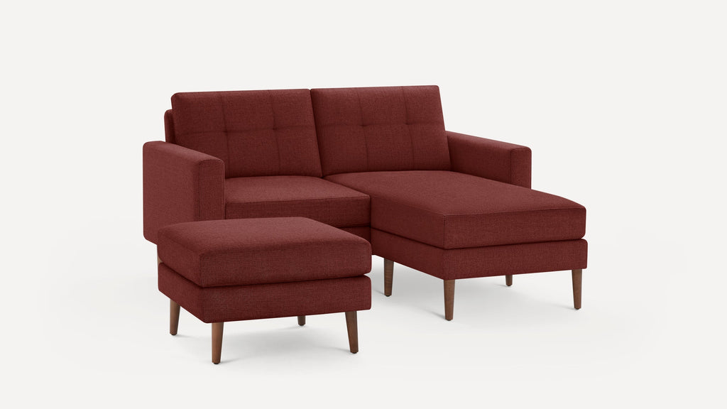 Modern sectional sofa with chaise lounge and matching ottoman in textured deep red fabric, supported by tapered wooden legs.