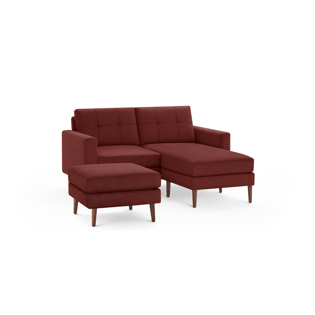Modern rust-colored sectional sofa with tufted back cushions, wooden legs, and matching ottoman on black background.