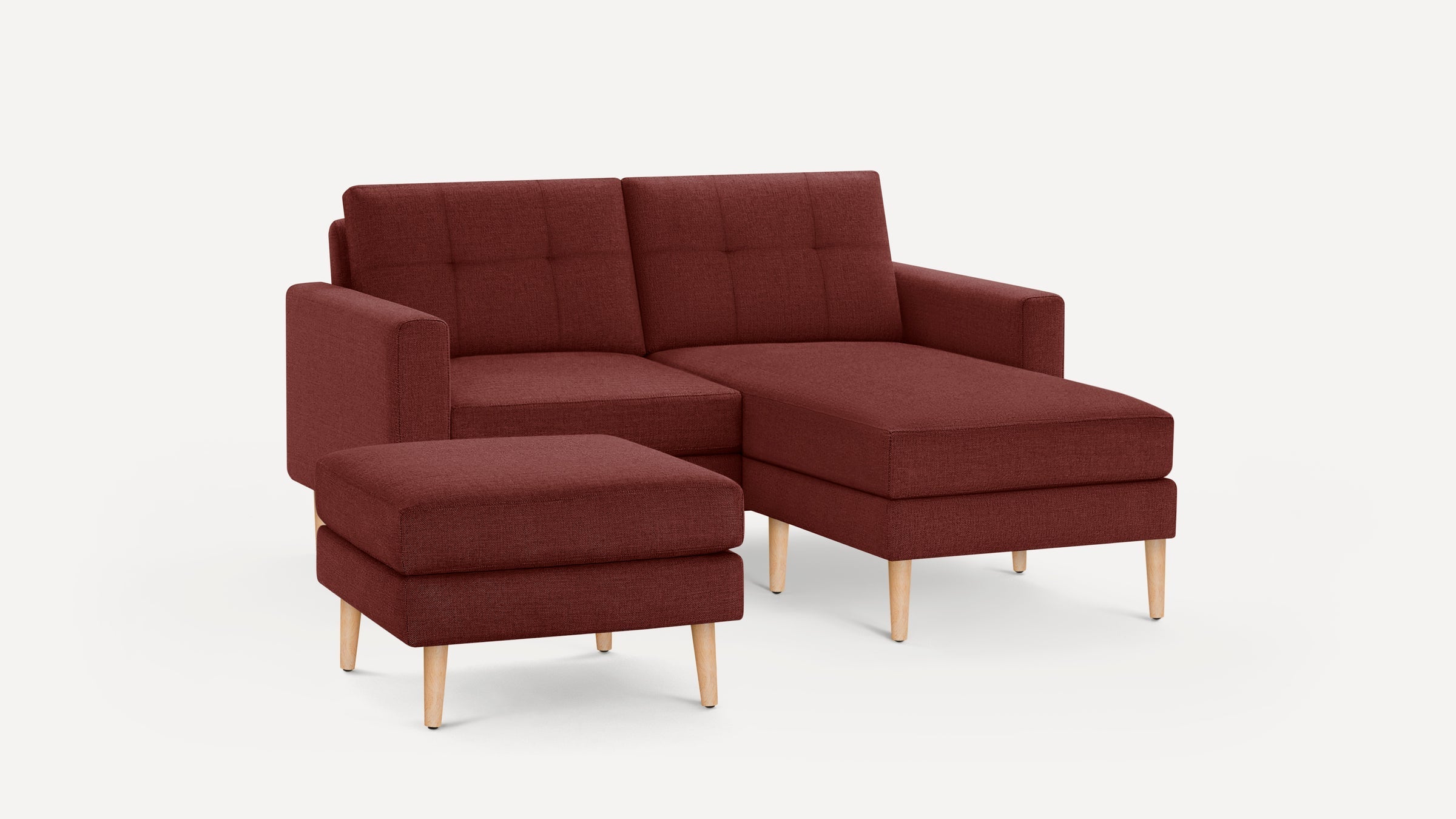 Modern rust-colored sectional sofa with tufted cushions, wooden legs, and a matching ottoman on a plain white background.