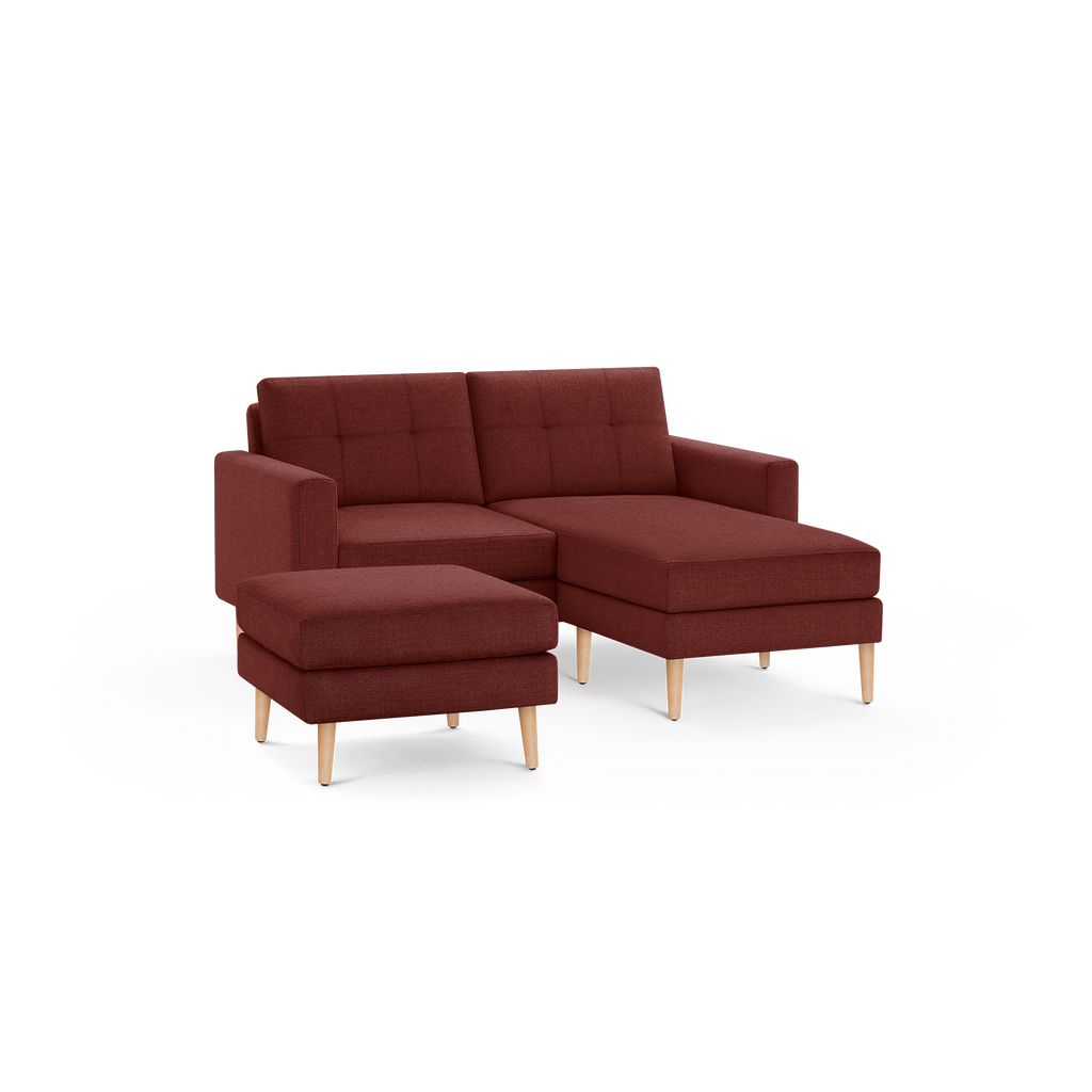 Modern L-shaped sectional sofa with chaise and matching ottoman, upholstered in deep red fabric with wooden legs.