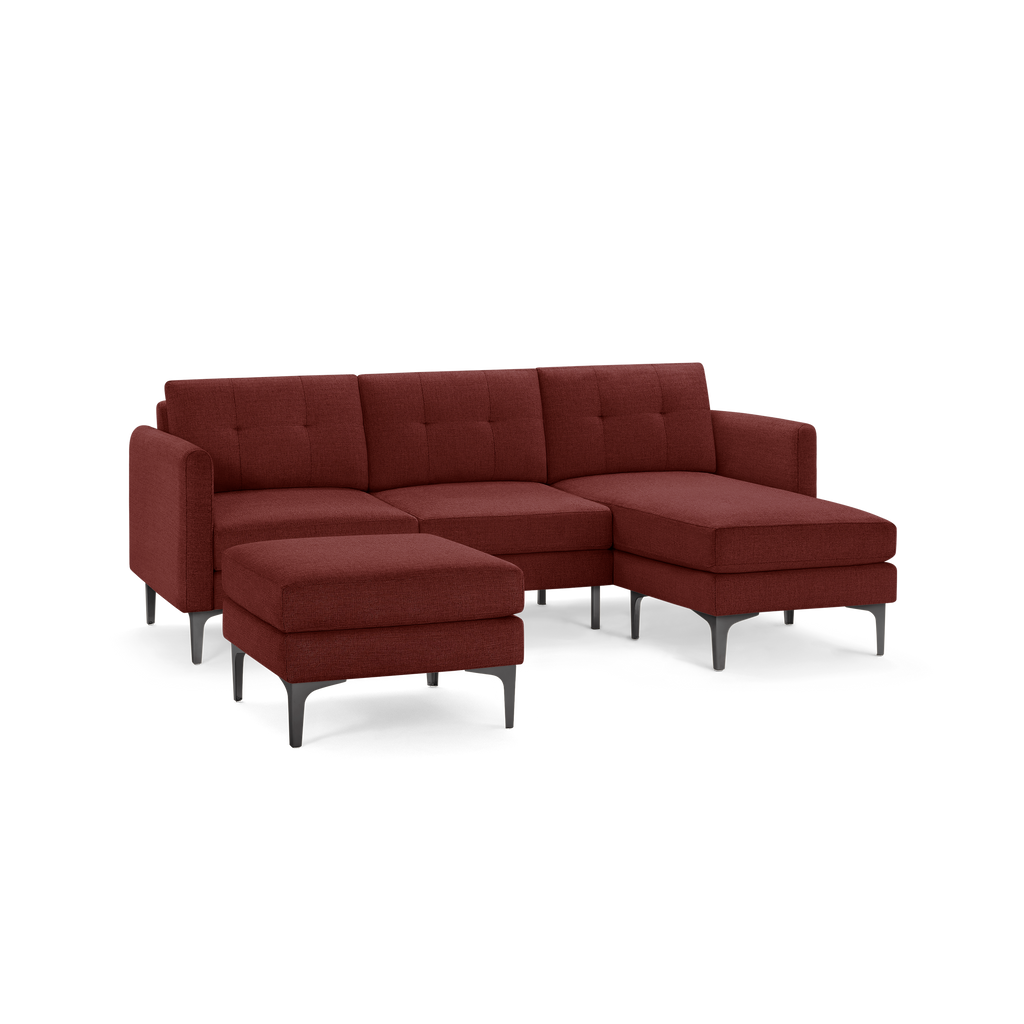 Modern sectional sofa with chaise lounge and matching ottoman, upholstered in deep red fabric with tufted cushions and black metal legs.