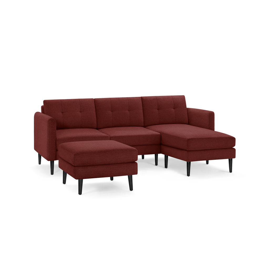 Modern sectional sofa with chaise lounge and matching ottoman, upholstered in deep red fabric with black wooden legs.