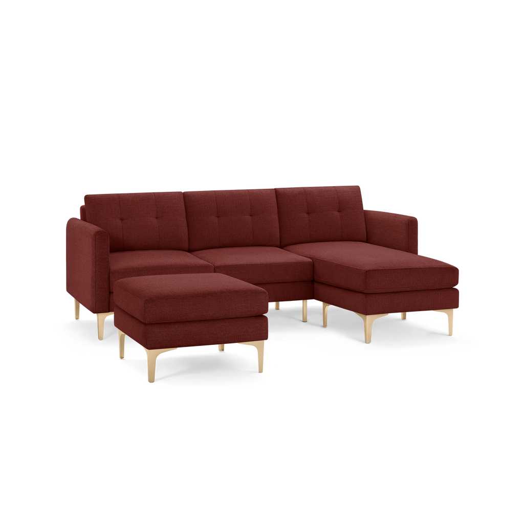 Modern red fabric sectional sofa with tufted cushions, chaise lounge on the right, and matching ottoman with light wooden legs.