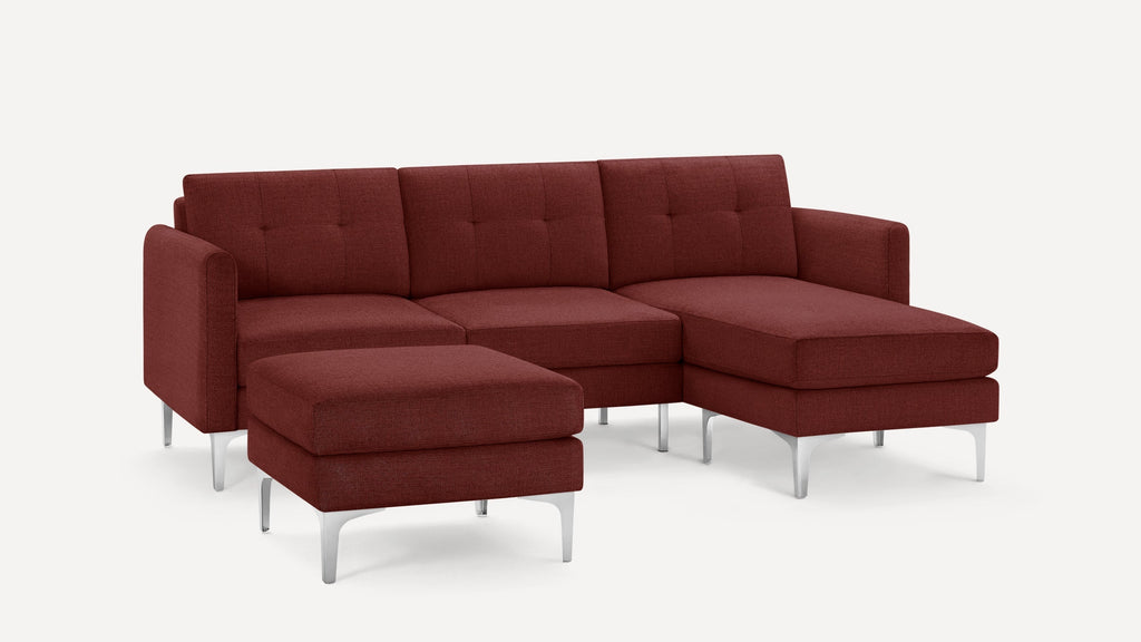 Modern deep red sectional sofa with a matching ottoman, tufted back cushions, and slim silver metal legs.