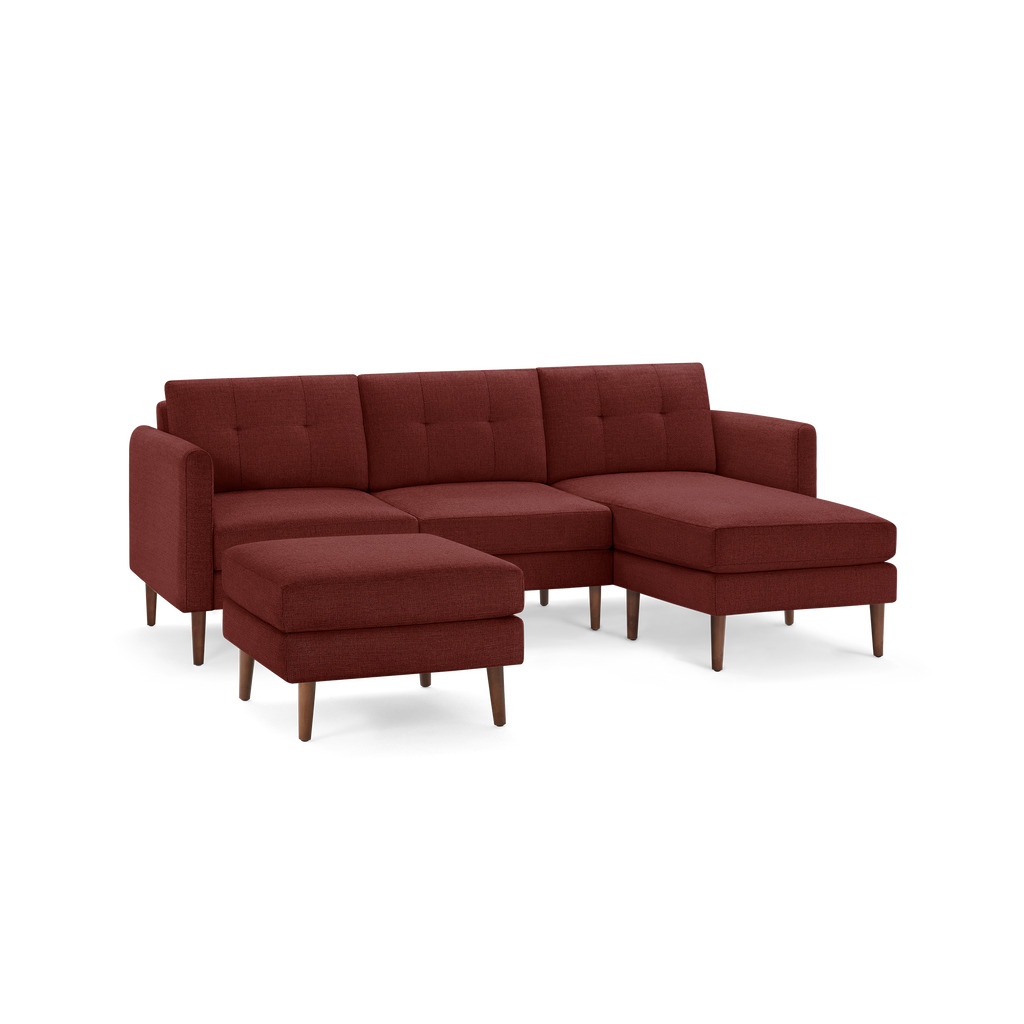 Modern L-shaped sectional sofa in deep red fabric with tufted back cushions and wooden tapered legs, including a matching ottoman.