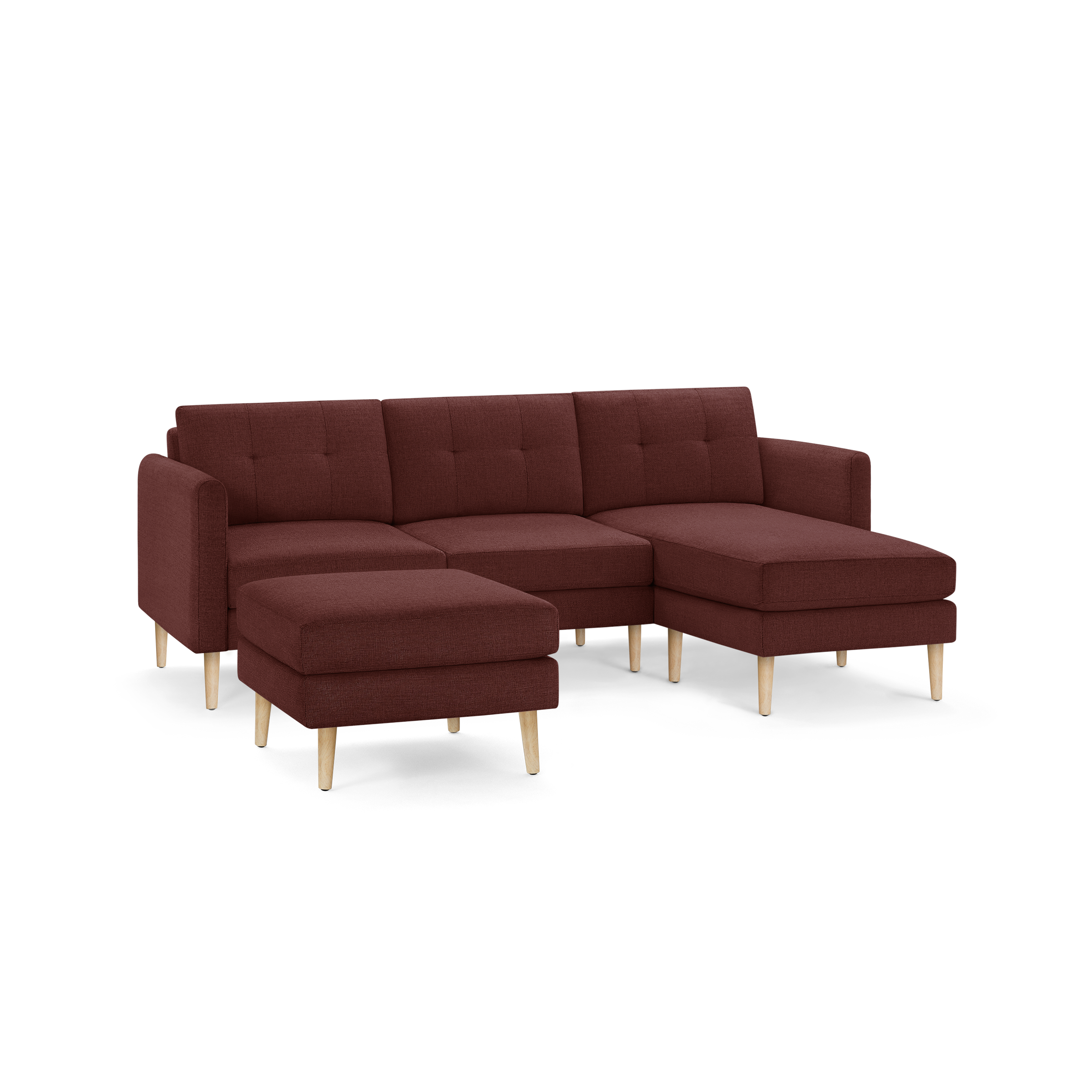 Modern L-shaped sectional sofa in deep red fabric with tufted back cushions and light wooden legs, featuring a matching ottoman.