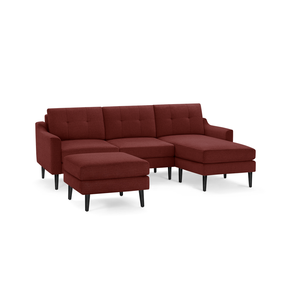 Modern sectional sofa with deep red fabric upholstery, tufted back cushions, black tapered wooden legs, and matching ottoman.