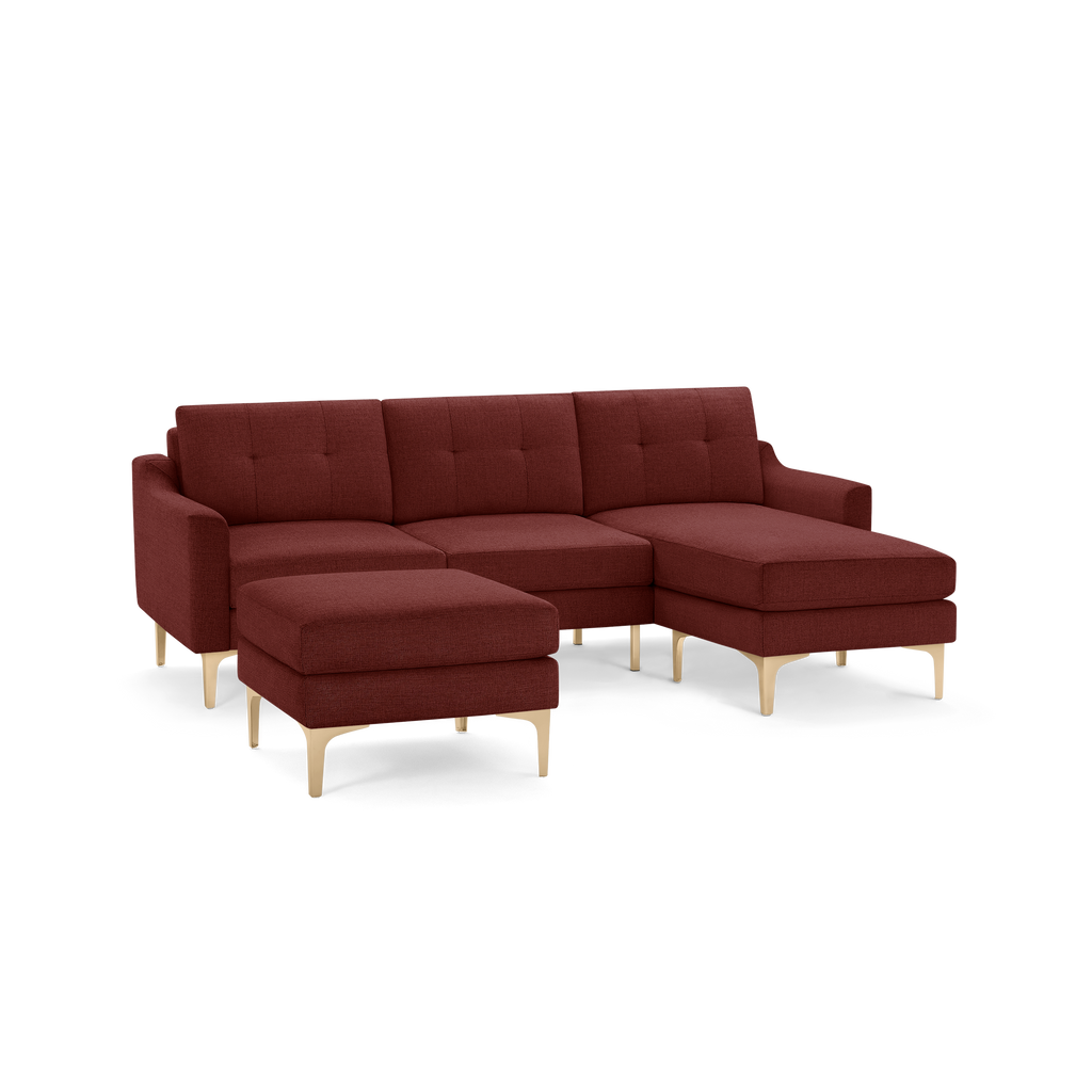 Modern sectional sofa with deep red fabric upholstery, tufted back cushions, and light wooden legs, including a matching ottoman.