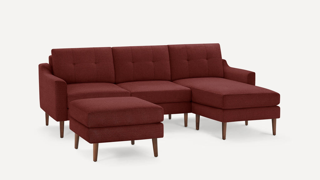 Modern mid-century style sectional sofa in deep red fabric with tufted cushions and wooden tapered legs, paired with matching ottoman.