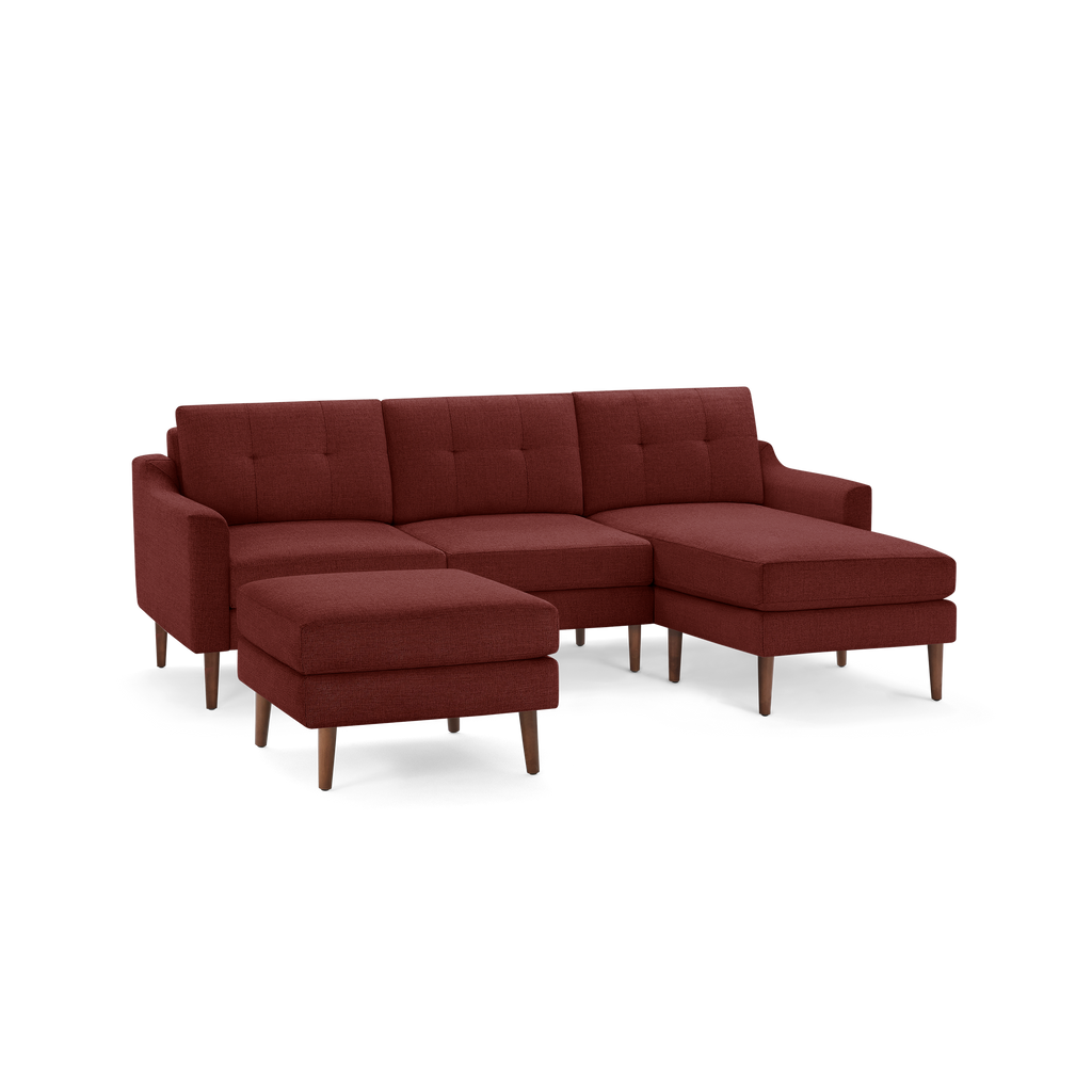 Rust-colored upholstered sectional sofa with tufted back cushions, a matching ottoman, and wooden tapered legs.