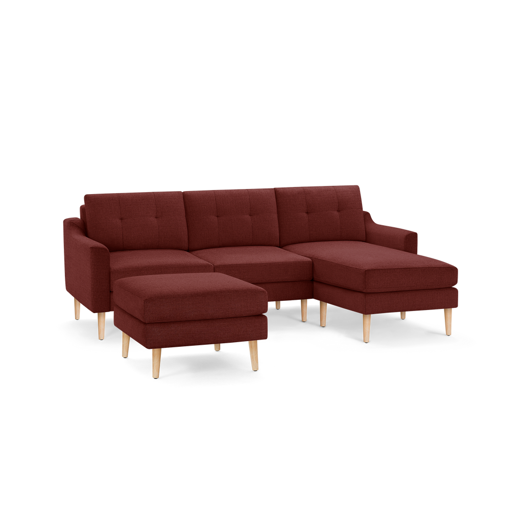 Modern L-shaped sectional sofa in deep red fabric with tufted cushions and light wooden tapered legs, including a matching ottoman.
