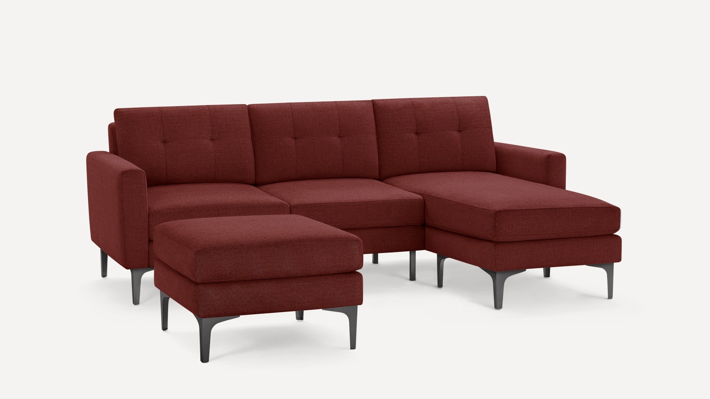 Modern L-shaped sectional sofa in deep red fabric with tufted cushions and black metal legs, accompanied by matching ottoman.