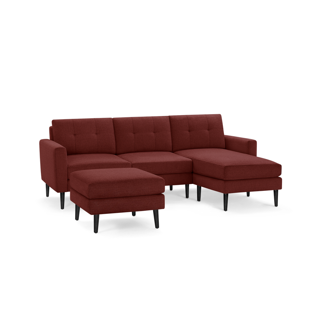 Modern sectional sofa in deep red fabric with tufted back cushions, black tapered legs, and matching ottoman.