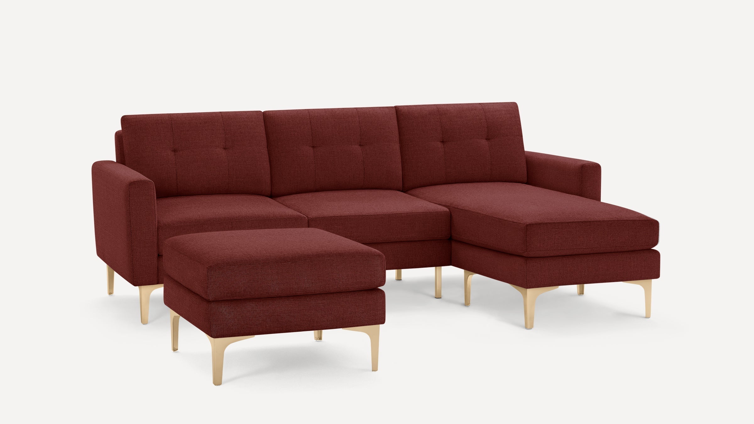 Modern red fabric sectional sofa with tufted cushions, slim armrests, wooden legs, and matching ottoman on white background.