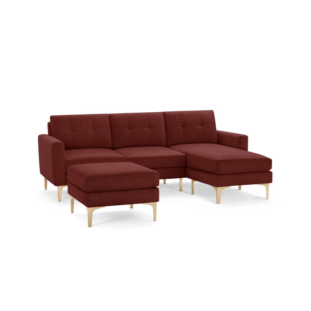 Modern sectional sofa with chaise and matching ottoman, upholstered in deep red fabric with light wooden legs.
