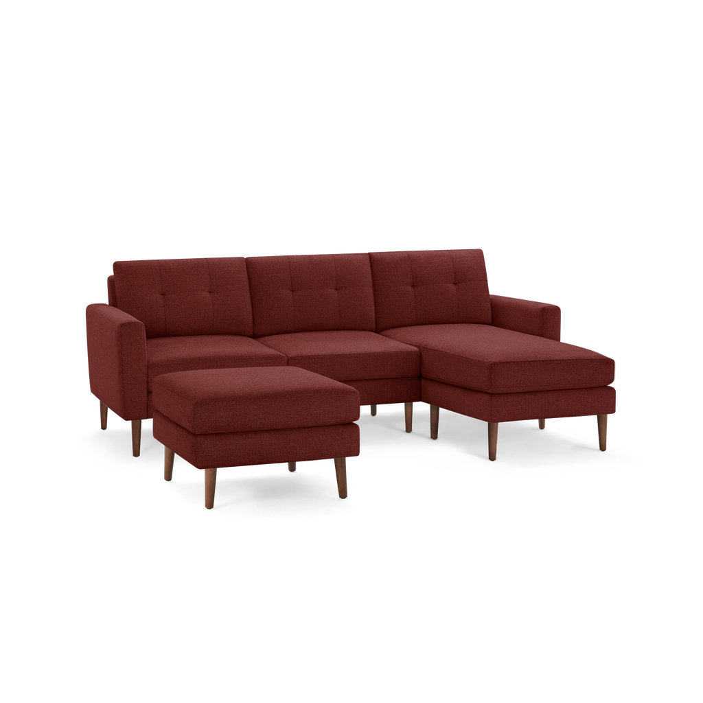 Mid-century modern sectional sofa with chaise and ottoman, upholstered in dark red fabric with wooden legs.