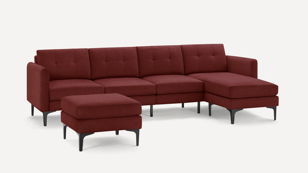 Modern sectional sofa in deep red fabric with tufted cushions, chaise lounge, and matching ottoman on black legs.