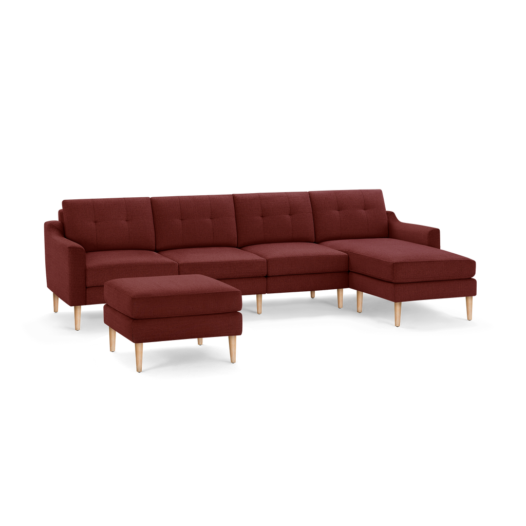 Modern deep red sectional sofa with tufted cushions, wooden legs, and matching ottoman on black background.