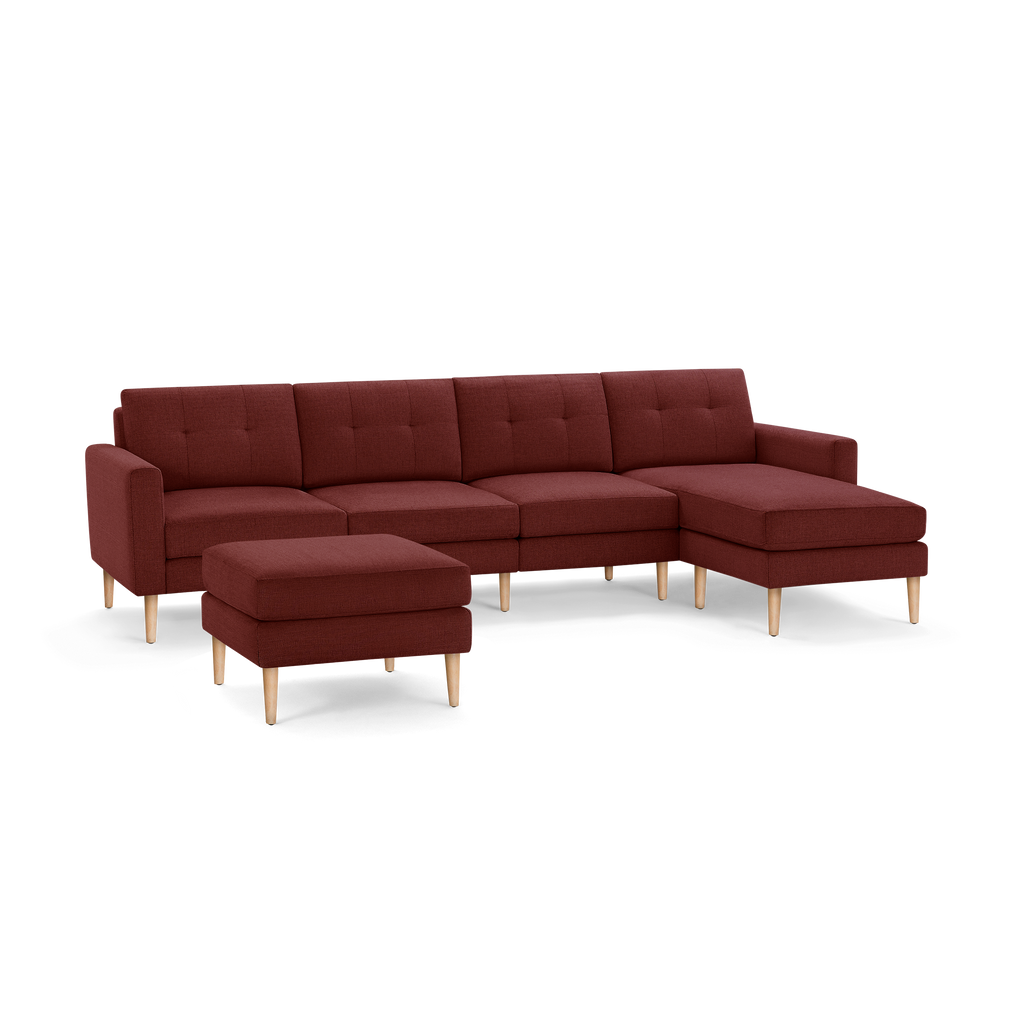 Modern L-shaped sectional sofa with chaise lounge and matching ottoman, upholstered in deep red fabric with wooden legs.