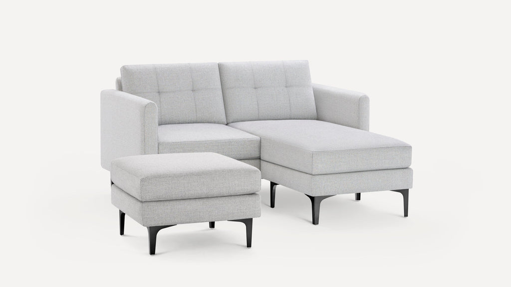 Light gray modern sectional sofa with tufted back cushions and a matching ottoman on black metal legs, displayed on white background.
