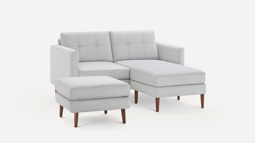 Light gray modern sectional sofa with chaise lounge and matching ottoman, featuring wooden tapered legs and tufted back cushions.