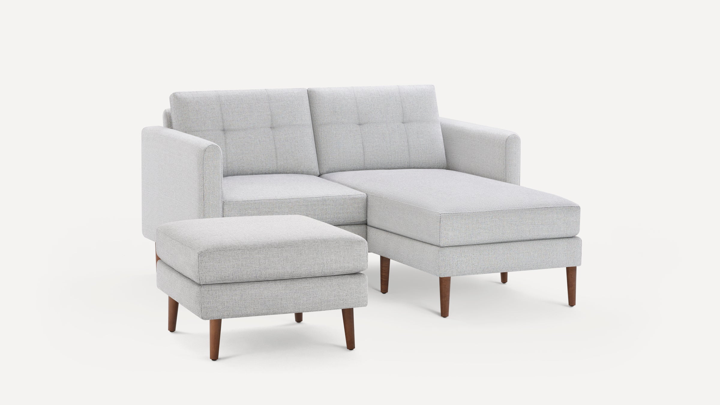 Light gray modern sectional sofa with chaise lounge and matching ottoman, featuring wooden tapered legs and tufted back cushions.