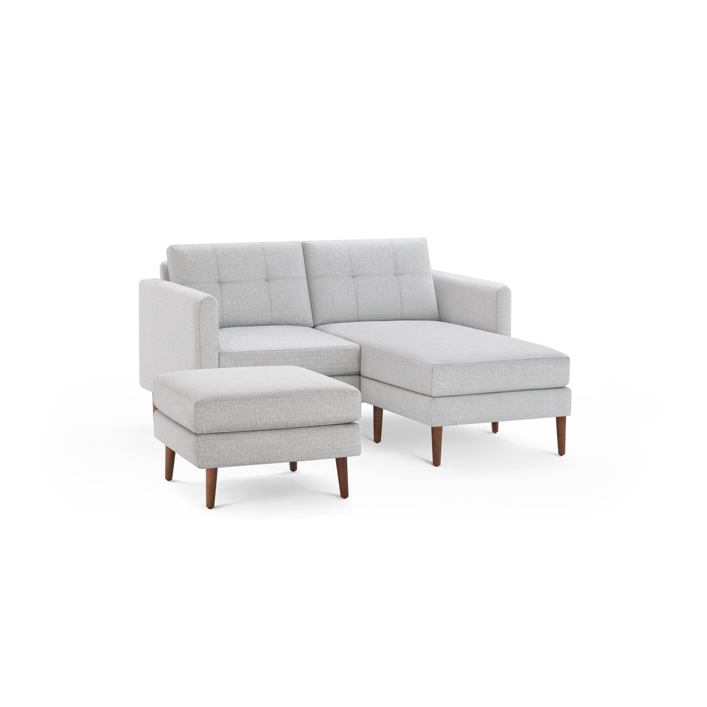 Light gray modern sectional sofa with tufted cushions and wooden legs, accompanied by a matching ottoman.