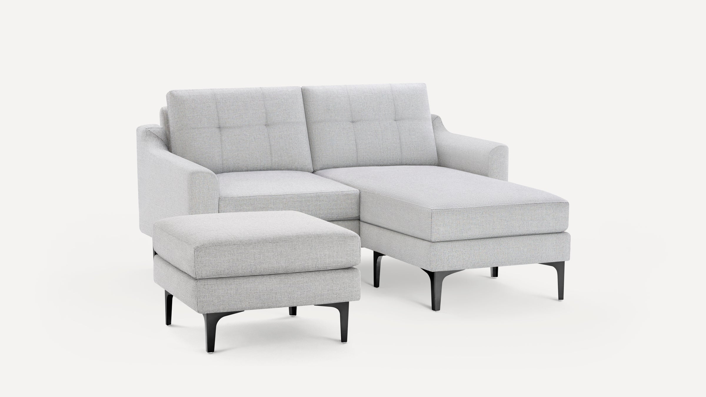 Light gray fabric sectional sofa with tufted back cushions and matching ottoman, featuring sleek black legs.