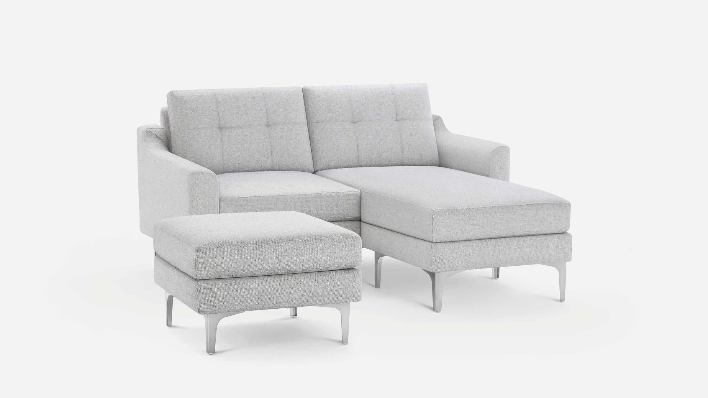 Light gray modern sectional sofa with tufted back cushions and matching ottoman on silver metal legs.