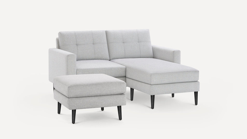 Light gray modern sectional sofa with tufted back cushions and matching ottoman, featuring black tapered wooden legs.