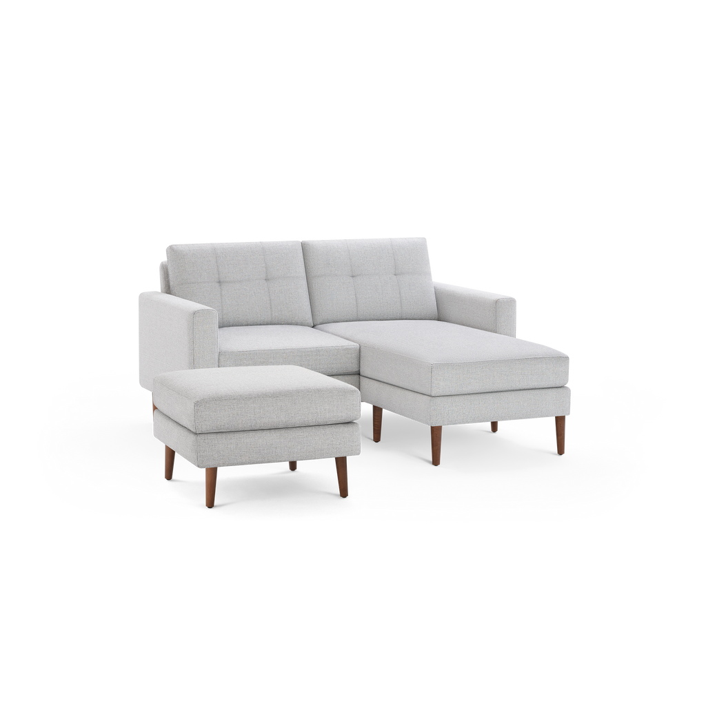 Light gray fabric sectional sofa with tufted back cushions, wooden legs, and a matching ottoman on black background.