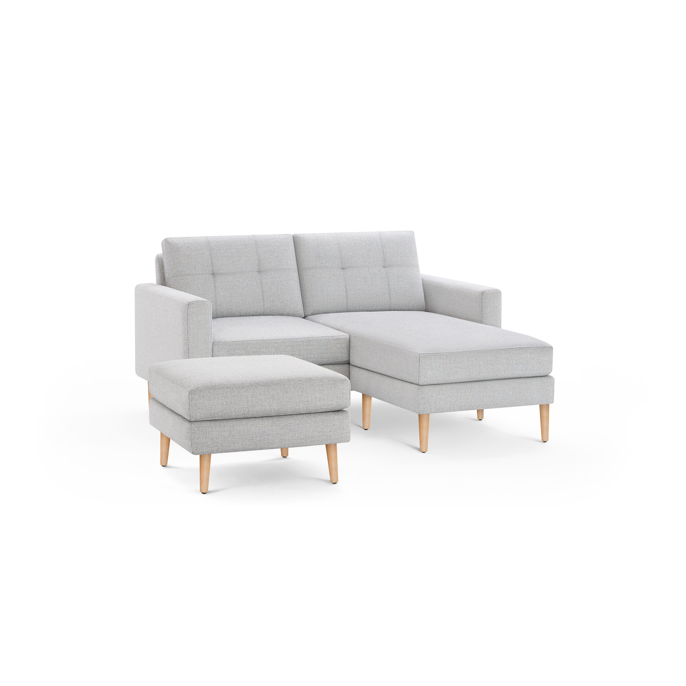 Light gray fabric chaise sofa with tufted back cushions, wooden legs, and a matching ottoman on a black background.