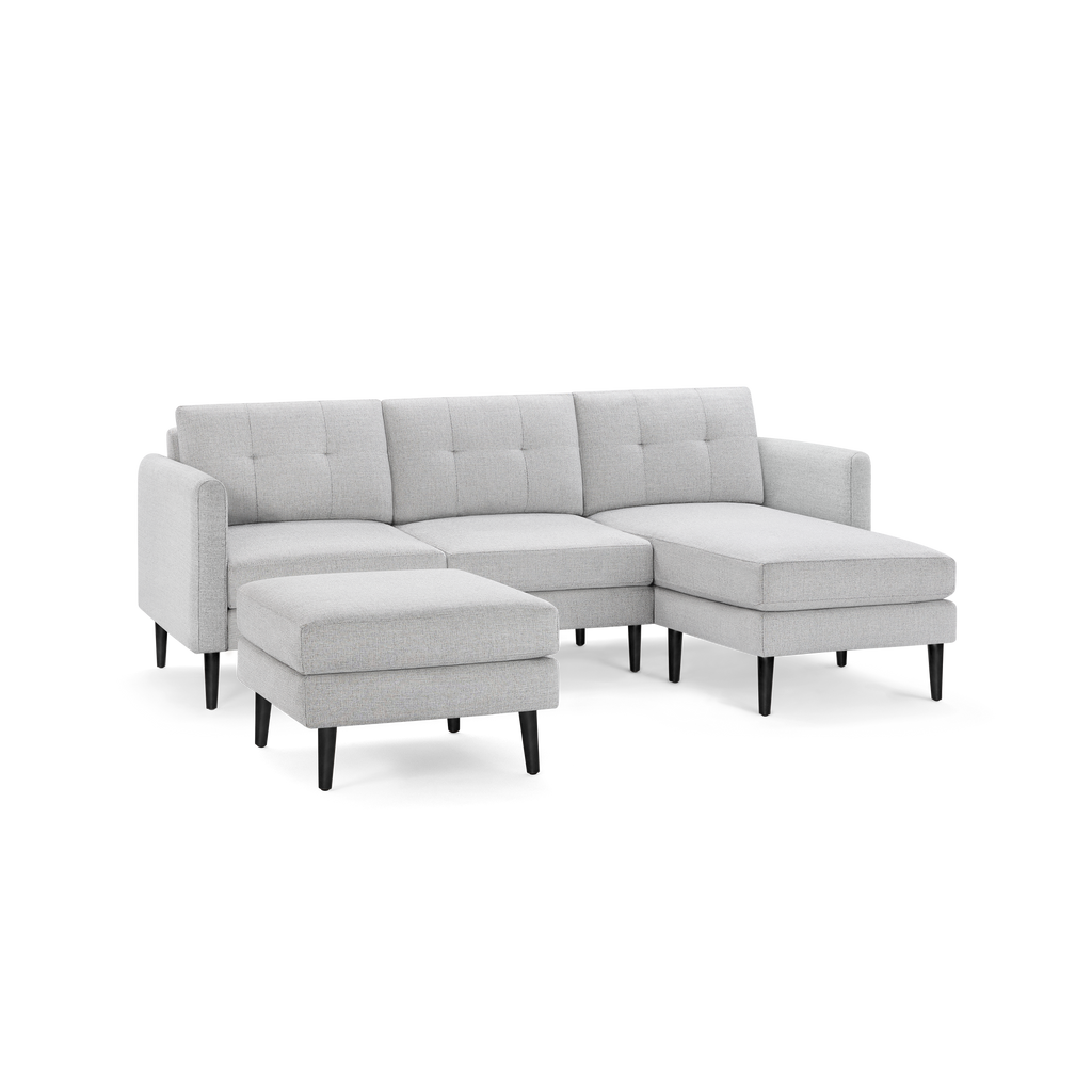 Light gray fabric sectional sofa with tufted back cushions, dark wooden legs, and a matching ottoman.