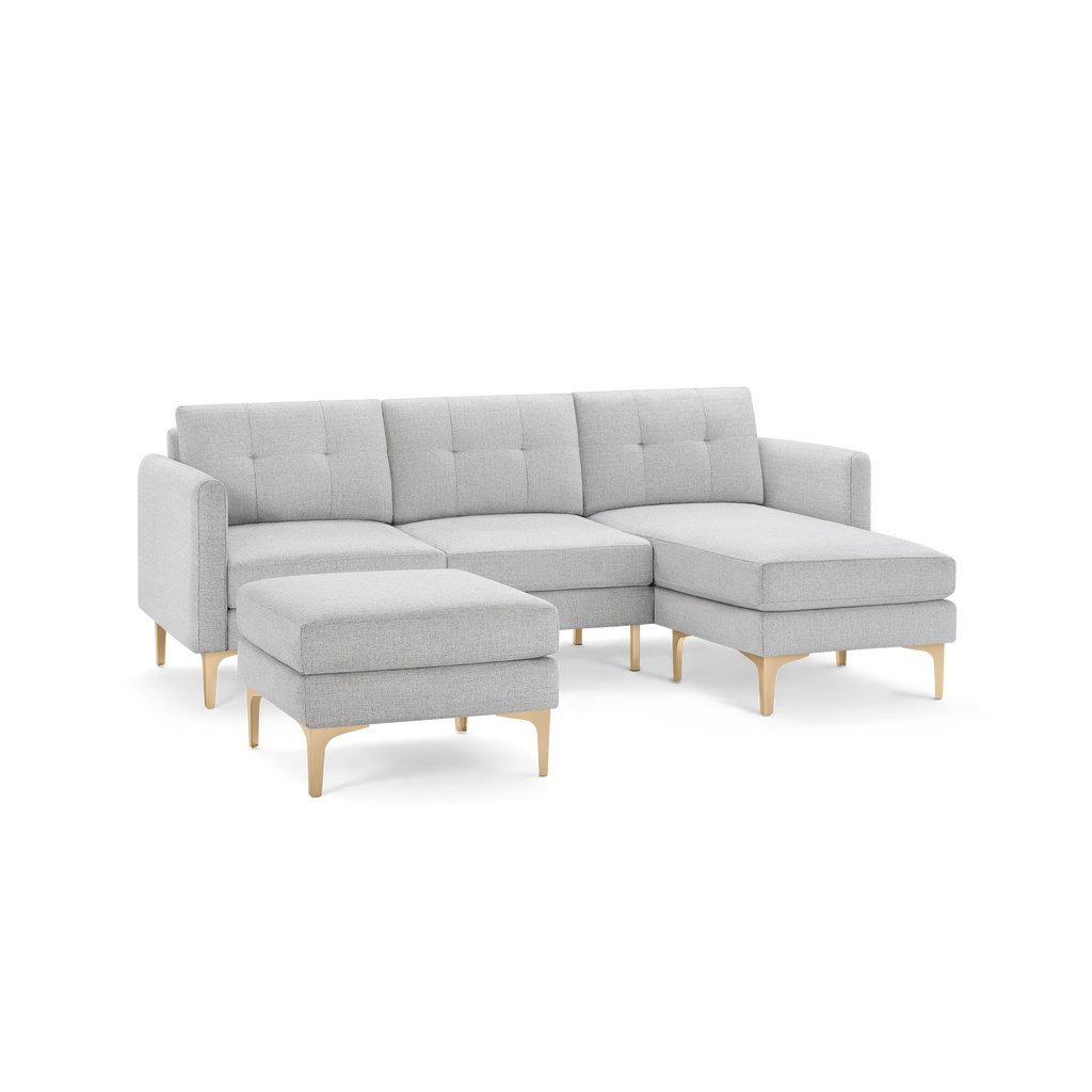 Light gray fabric sectional sofa with tufted cushions, wooden angled legs, and matching ottoman, modern minimalist design.