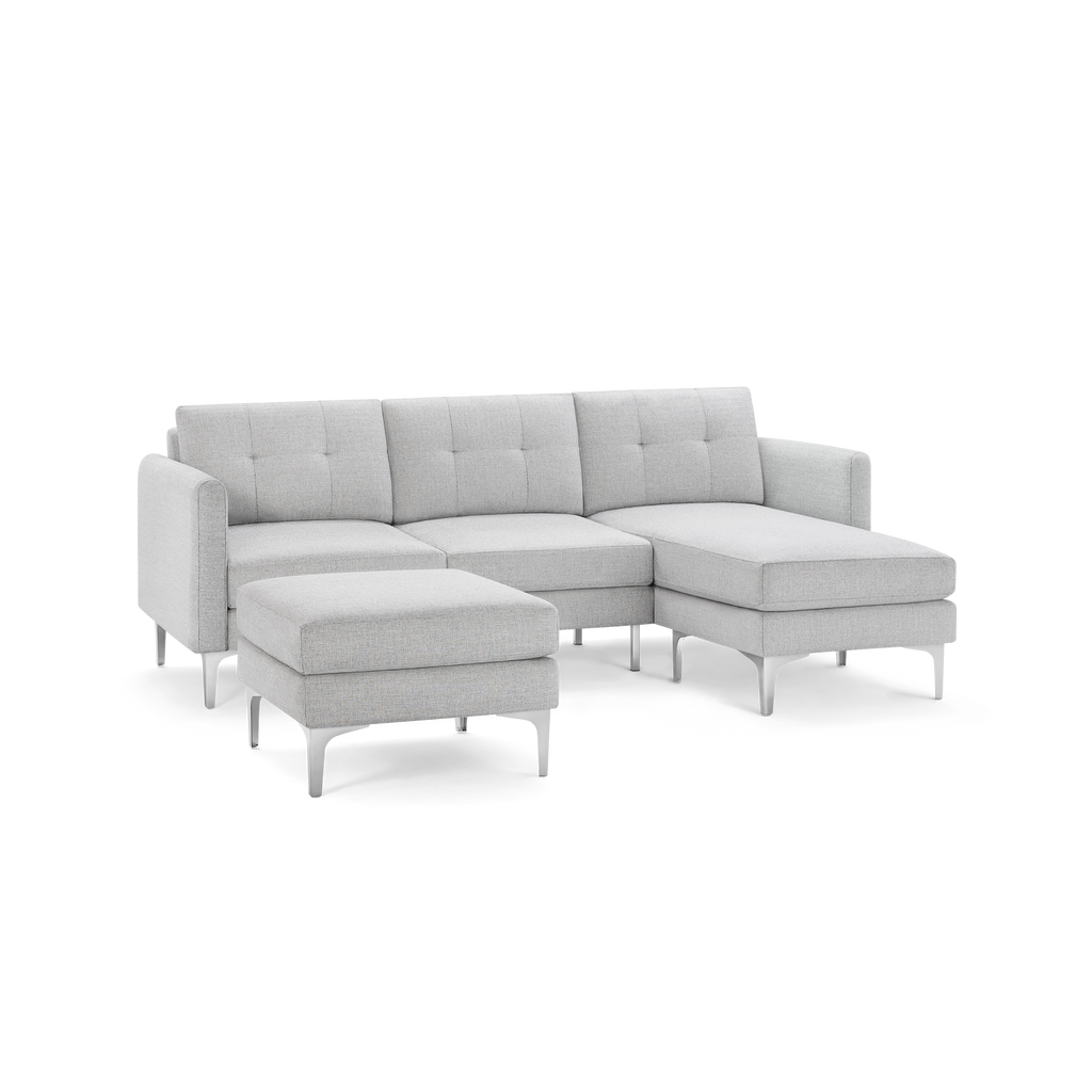 Light gray modern sectional sofa with chaise lounge and matching ottoman, featuring tufted cushions and angled metal legs.