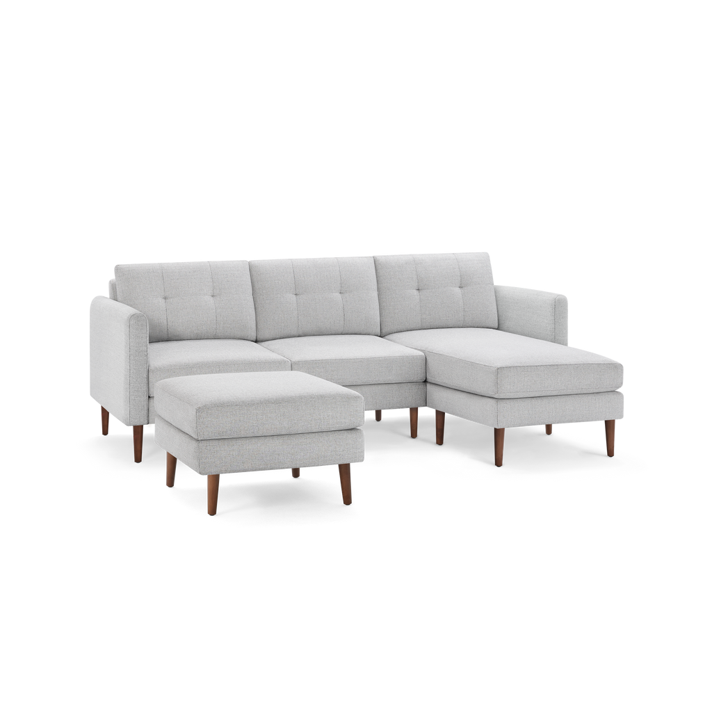 Light gray sectional sofa with tufted cushions, wooden legs, and a matching ottoman, designed for modern living rooms.