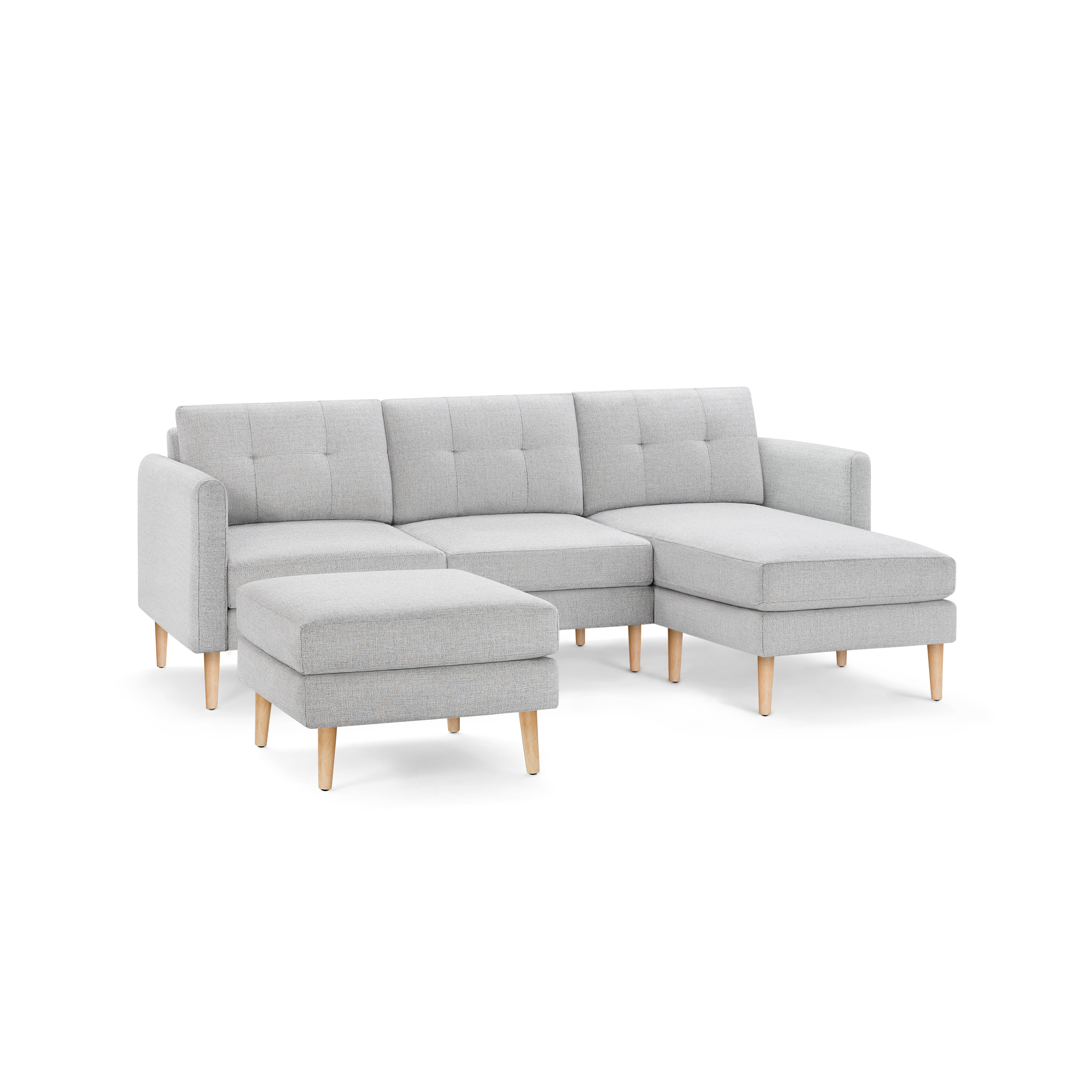 Light gray fabric L-shaped sectional sofa with tufted back cushions, matching ottoman, and wooden legs.