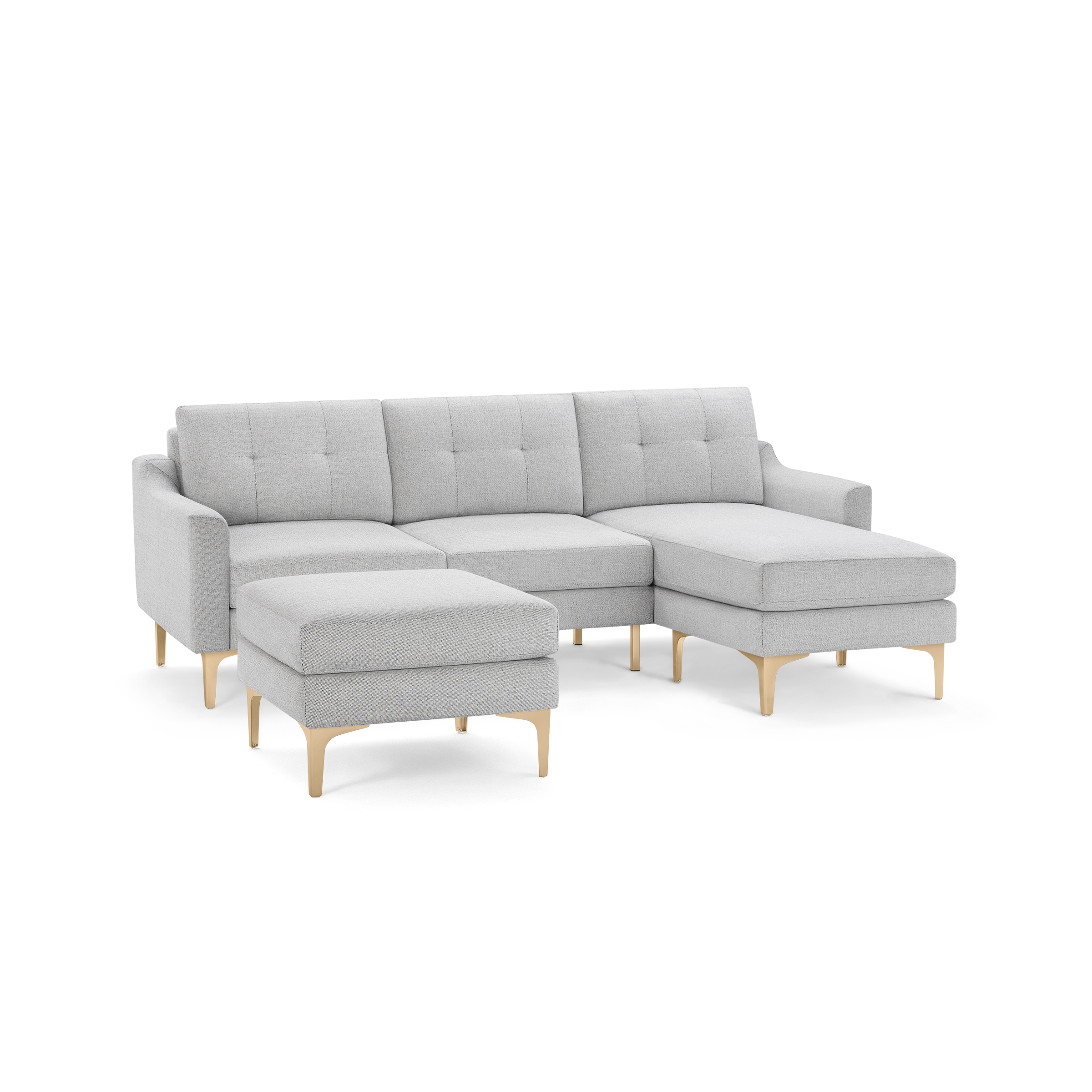 Light gray upholstered sectional sofa with tufted cushions, a chaise lounge on the right, and matching ottoman, both supported by gold metal legs.