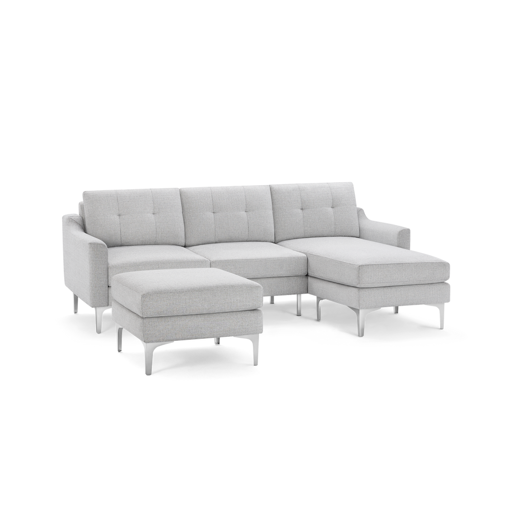 Light gray fabric sectional sofa with tufted back cushions, metal legs, and an ottoman. Modern and sleek design for living room comfort.