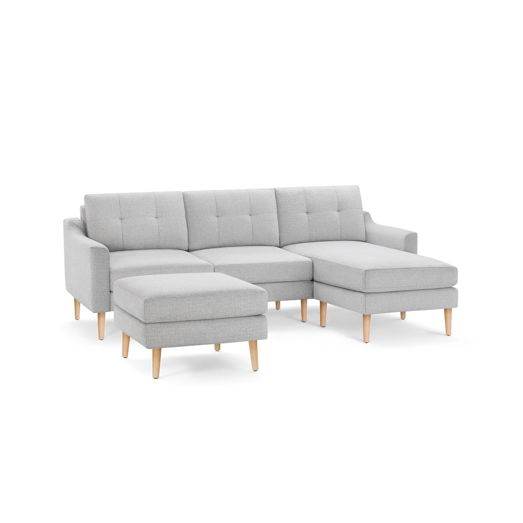Light gray modern sectional sofa with tufted cushions, wooden legs, and matching ottoman, featuring a right-side chaise lounge.