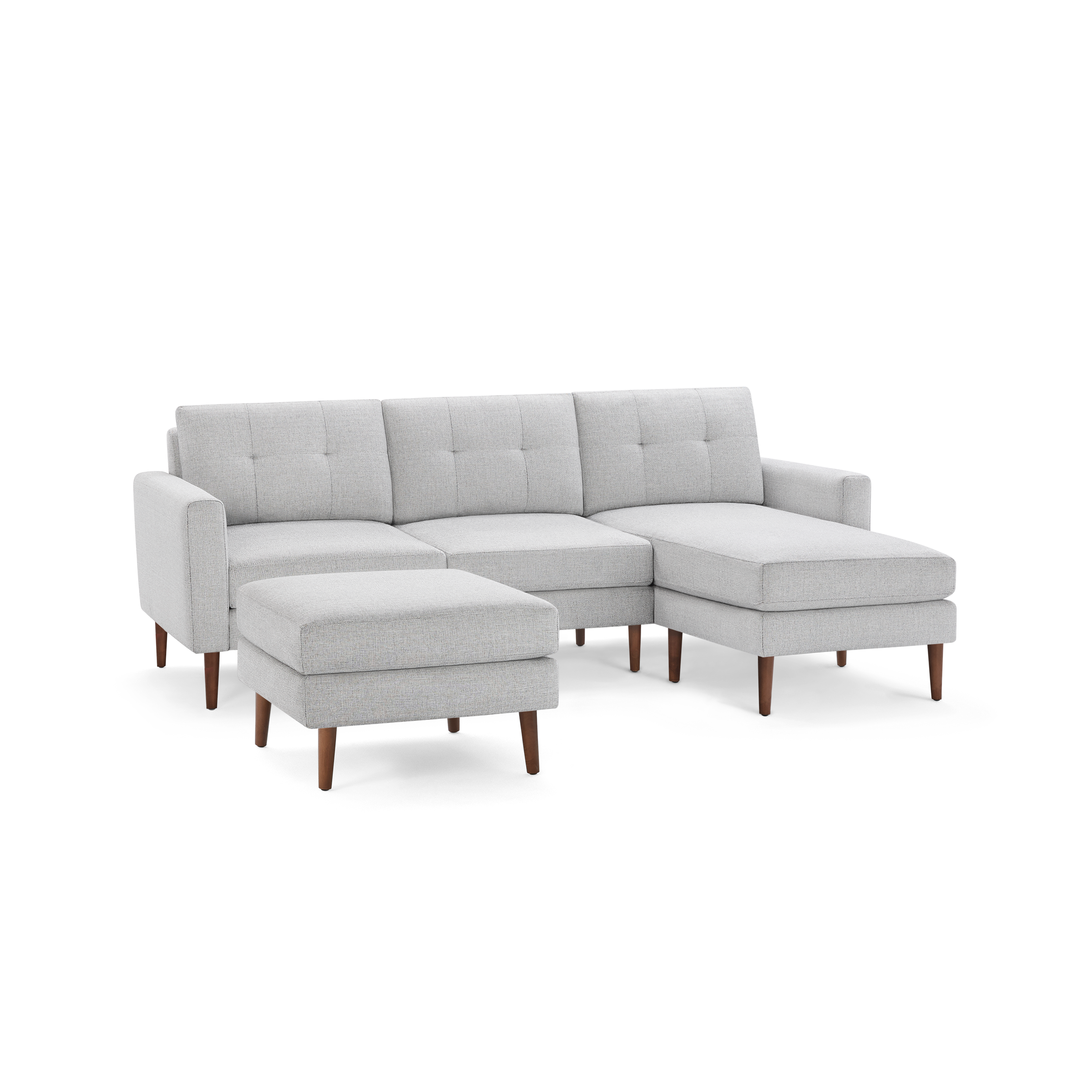 Light gray upholstered sectional sofa with tufted back cushions and wooden legs, including a matching ottoman.