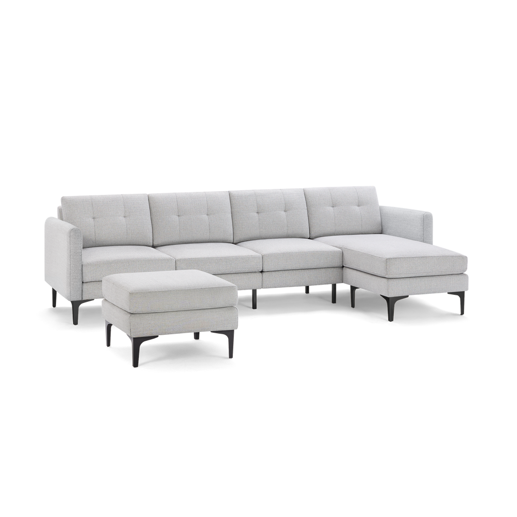 Light gray L-shaped sectional sofa with tufted cushions and matching ottoman, supported by black tapered legs.